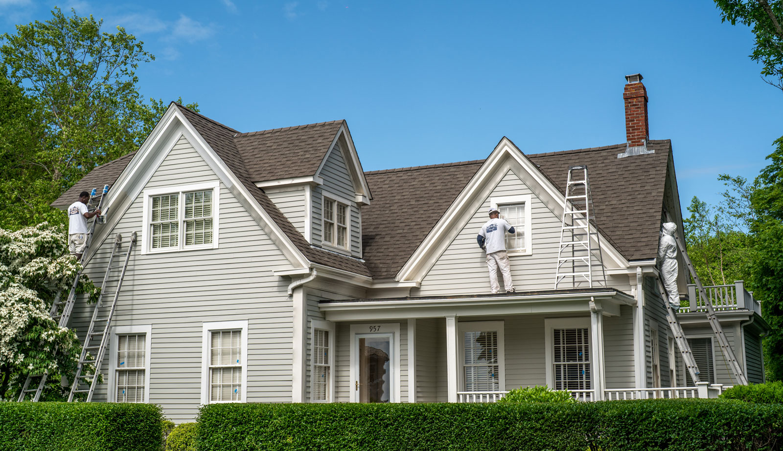 Three painters on ladders on side of house